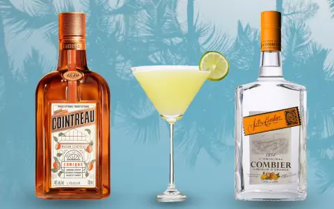 Cointreau kontra Triple Sec w koktajlach: pomarańczowy likier Cointreau i przezroczysty Combier obok drinka z limonką.