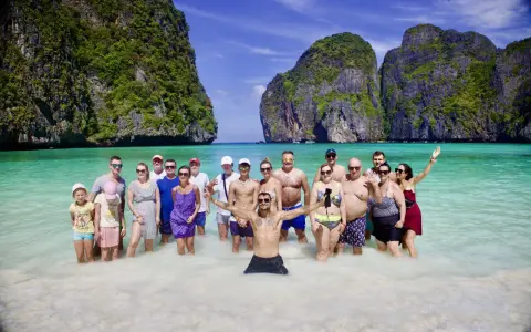Grupa ludzi cieszy się słońcem i turkusową wodą na plaży Maya Bay.