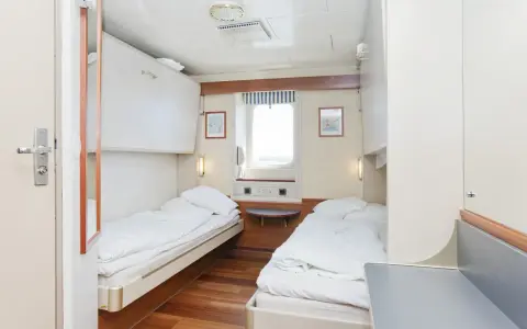Przytulna stena spirit kabiny z dwoma łóżkami, oknem i szafkami.
