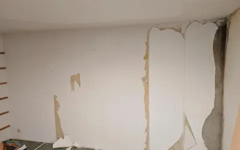 Renovierungsarbeiten: Alte Tapete wird entfernt, um die Wand für neues **Styropor tapezieren** vorzubereiten.