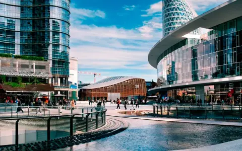 Scena urbana moderna con persone che passeggiano, un edificio IBM e grattacieli specchiati. Immagini di vita quotidiana in una città dinamica.