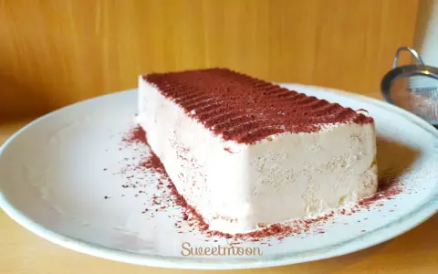 Un delizioso semifreddo al caffè, cosparso di cacao amaro, attende su un piatto bianco.