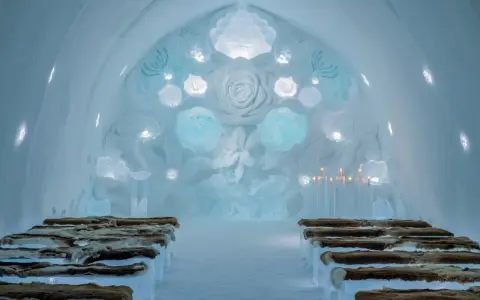 Vacker iskyrka i ett igloo hotell Sverige. Bänkar av is med renskinn, isrosor och levande ljus skapar en magisk atmosfär.