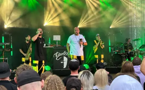 Zespół na scenie podczas festiwalu czochraj bobra fest. Wokalista śpiewa, grają saksofonista, trębacz i perkusista.