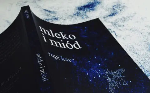 Okładka książki "Mleko i miód" Rupi Kaur z motywem pszczoły na granatowym tle w gwiazdy.