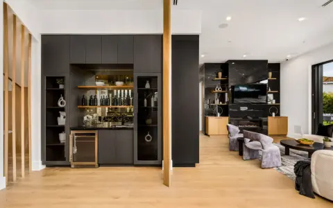 Elegante angolo bar in casa con bottiglie, cantinetta e mensole a vista.