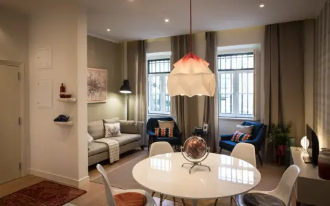 Una sala da pranzo moderna con tavolo bianco, sedie, divano, poltrone blu e un globo decorativo.