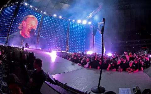James Hetfield śpiewa na koncercie Metalliki w Warszawie. Tłum szaleje, a gigantyczny ekran pokazuje zbliżenie na wokalistę.