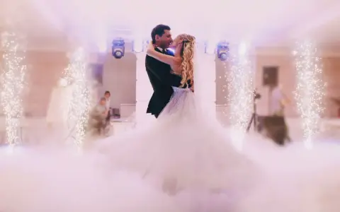 Para młoda tańczy w chmurach ciężkiego dymu, otoczona fontannami iskier.
