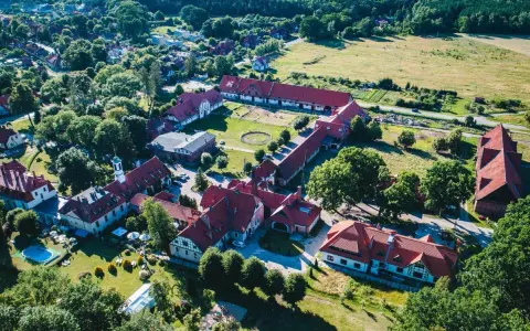 Widok z lotu ptaka na kompleks budynków hotelowych z czerwonymi dachami. Wiele pozytywnych kadyny folwark hotel & spa opinie potwierdza urok tego miejsca.