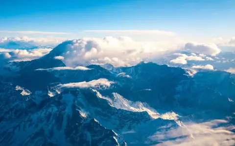 Majestatyczne góry z Aconcagua, skąpane w słońcu, otoczone chmurami. Widok z lotu ptaka na ośnieżone szczyty.