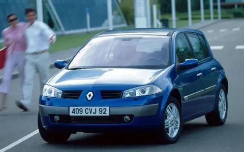 Niebieski Renault Megane 2 na drodze, z parą ludzi w tle.