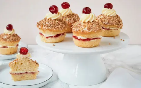 Frankfurter Kranz Muffins: kleine Kuchen mit Buttercreme, Marmelade und Mandelsplittern, gekrönt von einer Kirsche.
