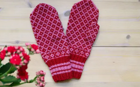 Två stickade vantar i rött och rosa med diamantmönster. Perfekt för dig som söker stickbeskrivningar gratis för att skapa egna.