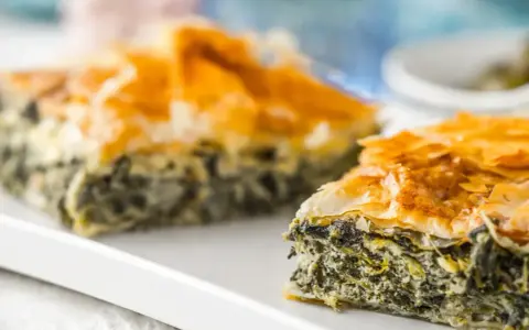Chrupiąca spanakopita z warstwami ciasta filo i zielonym nadzieniem ze szpinaku i sera.