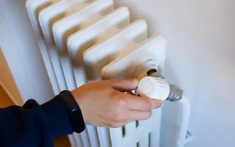 Ajustando el termostato de un radiador para optimizar la calefacción central en comunidades de vecinos.
