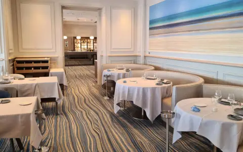 Élégant bistro à Saint-Malo, tables dressées, ambiance chic avec une fresque marine au mur.