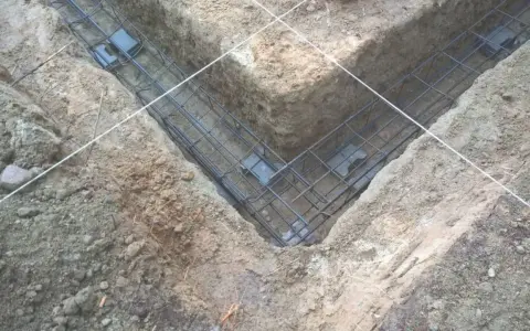 Zbrojenie fundamentów prefabrykowanych w wykopie. Stalowe pręty tworzą siatkę, gotową do zalania betonem.