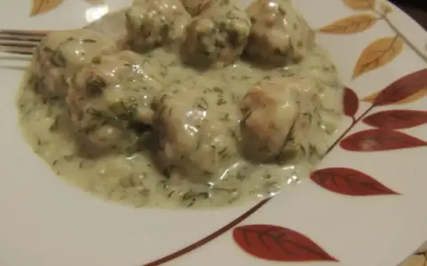 Pyszne pulpety w sosie koperkowym, podane na talerzu z liśćmi.