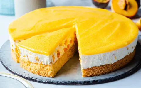 Eine saftige Pfirsich Maracuja Torte mit Biskuitboden, cremiger Füllung und fruchtigem Topping. Ein Stück ist bereits angeschnitten.