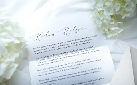 List do rodziców z podziękowaniami. Białe kwiaty i elegancka koperta tworzą tło dla wzruszających słów.