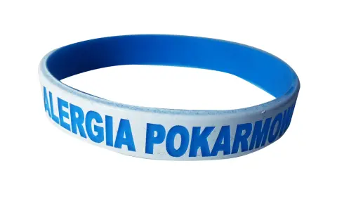 Niebieska opaska na ręce z napisem "ALERGIA POKARMOWA" informuje o problemach z jedzeniem.