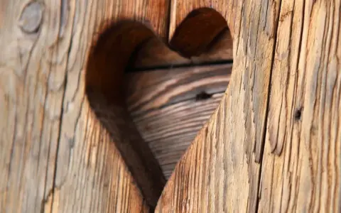 Corazón tallado en madera con textura de envejecer madera, mostrando vetas y grietas que cuentan historias.