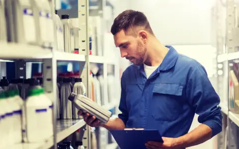 Mechanik sprawdza, czy olej silnikowy ma datę ważności, przeglądając zapasy w magazynie.