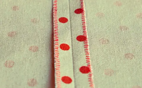 Tessuto a pois rossi con cucitura a punto sopraggitto a mano che crea un dettaglio decorativo.