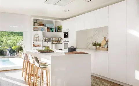 Cocina blanca moderna con isla central, estanterías abiertas y vistas al jardín. Ideas para decorar pared cocina blanca con estilo minimalista.