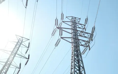 Wysokie słupy energetyczne z przewodami, przypominające o potrzebie oszczędzania i rozsądnym zarządzaniu abonamentem za prąd.