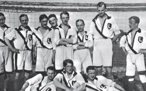 Drużyna piłkarska Legii Warszawa w strojach z lat 30. XX wieku, pozująca do zdjęcia.