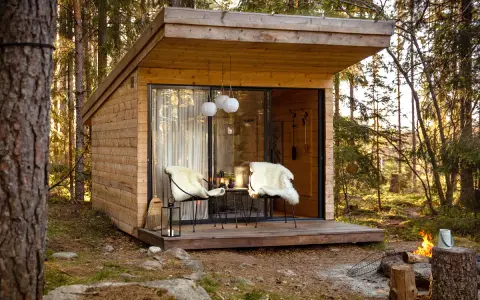 Mysig koja i skogen, perfekt för att bo i som ett skogshotell. Två fårskinnsbeklädda stolar på altanen inbjuder till avkoppling.