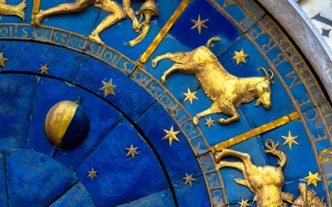 Złoty koziorożec na niebieskiej tarczy zegara astronomicznego, otoczony gwiazdami i cyframi. Dlaczego koziorożec milczy? Może czeka na swój czas.