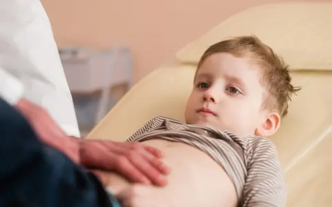 Un bambino viene visitato per sospetto neuroblastoma. Il medico gli tocca delicatamente l'addome.