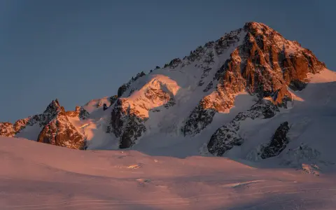 Ośnieżone szczyty Alp o wschodzie słońca, oświetlone złotym blaskiem. Widok na trasę Haute Route, gdzie lodowce i skaliste zbocza tworzą majestatyczny krajobraz.