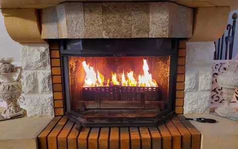 Chimenea de leña con llamas vibrantes. El fuego ilumina el interior de la chimenea, creando un ambiente acogedor. Los pellets en la base de la chimenea se queman, alimentando las llamas.