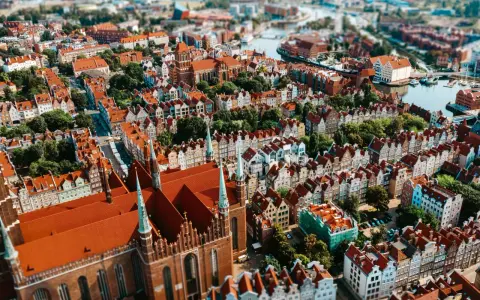 Widok z lotu ptaka na zabytkowe miasto z ceglaną katedrą i kolorowymi kamienicami.