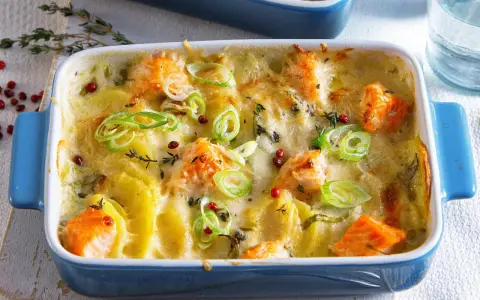 Herzhaftes Fischgericht mit Kartoffeln, überbacken mit Käse und garniert mit Frühlingszwiebeln und rosa Pfeffer.