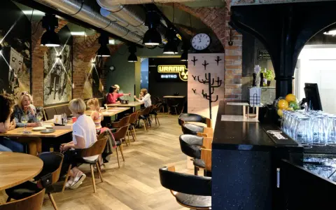 Wnętrze restauracji Urania Bistro z ludźmi przy stołach i barem.
