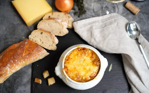 Herzhaftes Zwiebelsuppen-Rezept: goldbraun überbackene Suppe mit Käse, Baguette und Zwiebeln.
