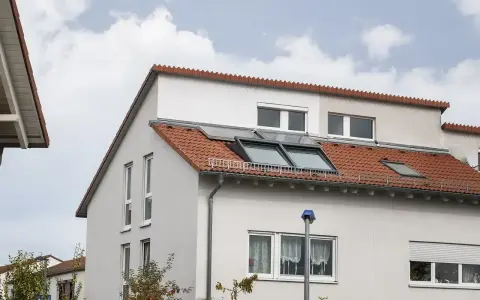 Ein Haus mit roten Ziegeln und Dachfenstern. Das Dach ist ein Pultdach, das nach einer Seite abfällt.
