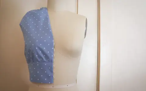Mannequin de couture présentant un corsage bleu à pois blancs, esquisse d'une future robe de mariée couture.