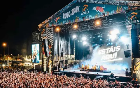 Multitud en concierto, luces brillantes y humo en el escenario. El cartel dice "Love to Rock".