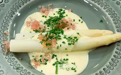 Vit sparris i en krämig sås till sparris, toppad med örter och rosa rom. En delikat rätt.