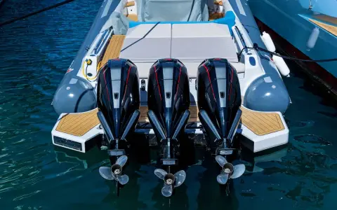 Trois puissants moteurs hors-bord noirs et rouges, prêts à propulser une chaise de luxe sur l'eau.