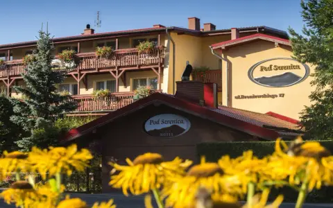 Hotel Pod Szrenicą w Szklarskiej Porębie, otoczony zielenią i kwitnącymi kwiatami, zaprasza na wypoczynek.