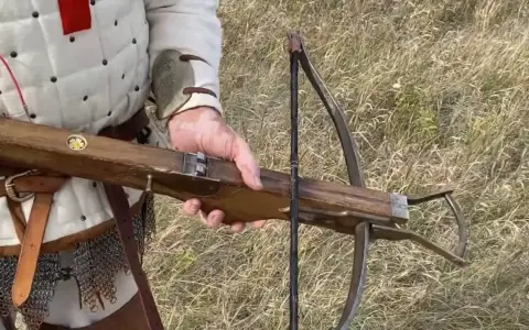Una ballesta de madera, similar a la ballesta Leonardo da Vinci, en manos de un guerrero con armadura.