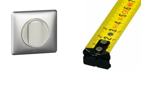 Interrupteur Legrand en métal brossé et mètre ruban jaune. Mesure de la hauteur interrupteur.