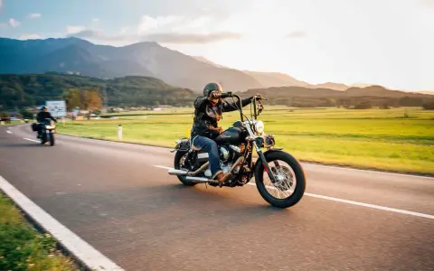 Motociclista in viaggio su una strada panoramica, un'atmosfera da European Bike Week con montagne sullo sfondo.